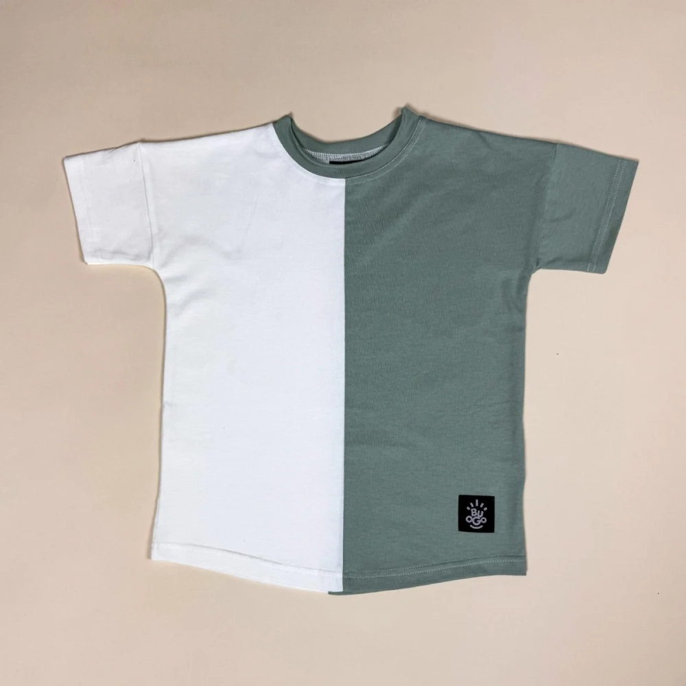 Dwukolorowy t-shirt Moss rozłożony na jasnym tle — połowa biała, połowa miętowa, pastelowo zielona, z subtelną metką (logo Buogo) na dole, idealny dla małych miłośników komfortu i stylu.