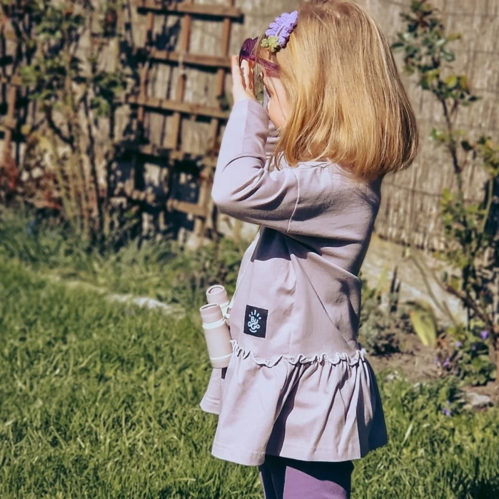 Dziewczynka w jagodowym, fioletowym longlseeve Blossom marki Buogo bawiąca się w ogrodzie – polska, wygodna odzież dziecięca premium